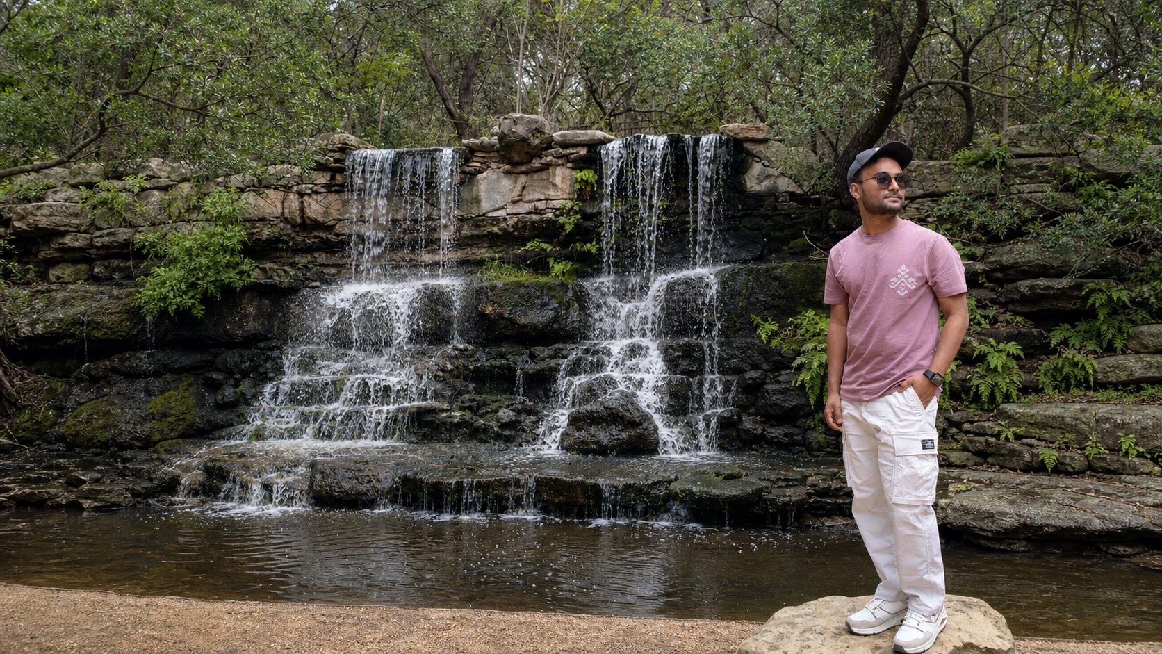 Pratik Kedar standing beside a waterfall